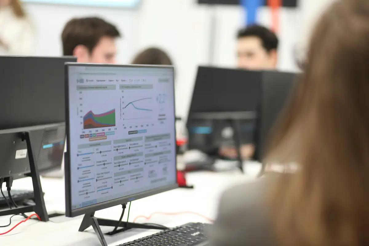 Personas trabajando frente a monitores que muestran datos y gráficos