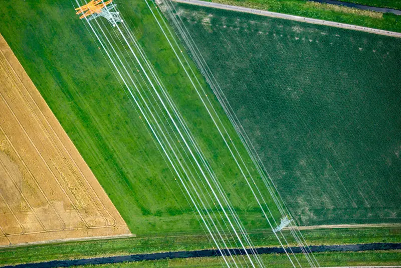 Líneas eléctricas de alta tensión atravesando campos agrícolas, vista aérea